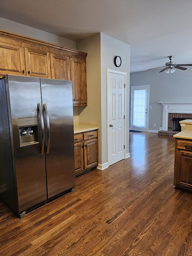 kitchen with a fireplace, stainless steel fridge, dark hardwood / wood-style flooring, and ceiling fan