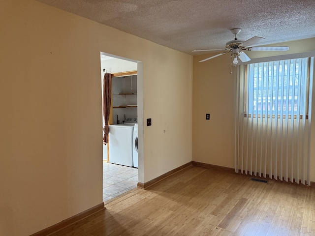 unfurnished room with a textured ceiling, washer / clothes dryer, light hardwood / wood-style flooring, and ceiling fan