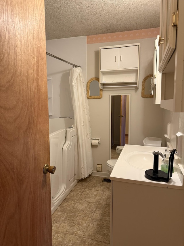 full bathroom featuring toilet, a textured ceiling, and shower / tub combo