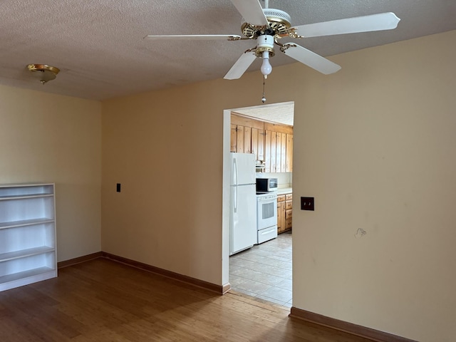 spare room with ceiling fan, a textured ceiling, and light wood-type flooring