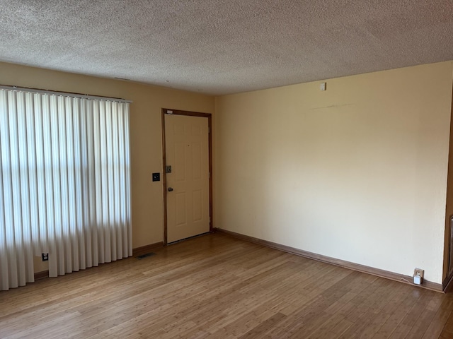 unfurnished room featuring light wood-type flooring and a textured ceiling