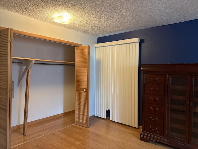 unfurnished bedroom with wood-type flooring, a textured ceiling, and a closet