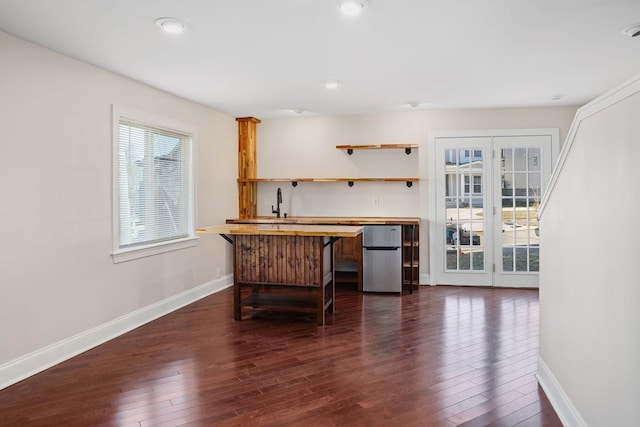 bar featuring butcher block countertops, stainless steel refrigerator, dark hardwood / wood-style flooring, and sink