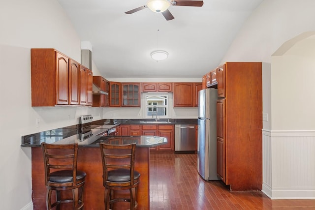 kitchen with a breakfast bar, lofted ceiling, dark wood-type flooring, appliances with stainless steel finishes, and kitchen peninsula