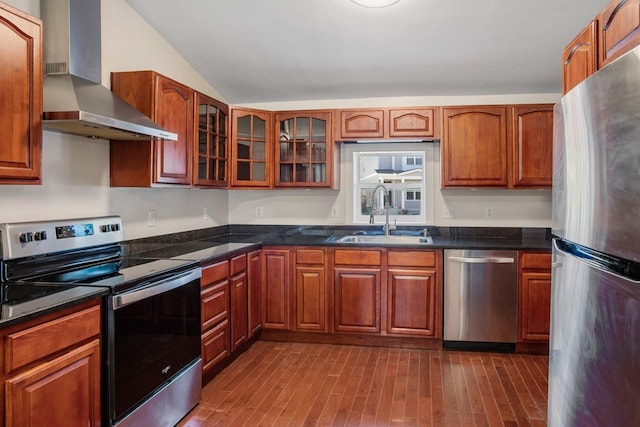 kitchen with hardwood / wood-style floors, wall chimney range hood, sink, vaulted ceiling, and appliances with stainless steel finishes