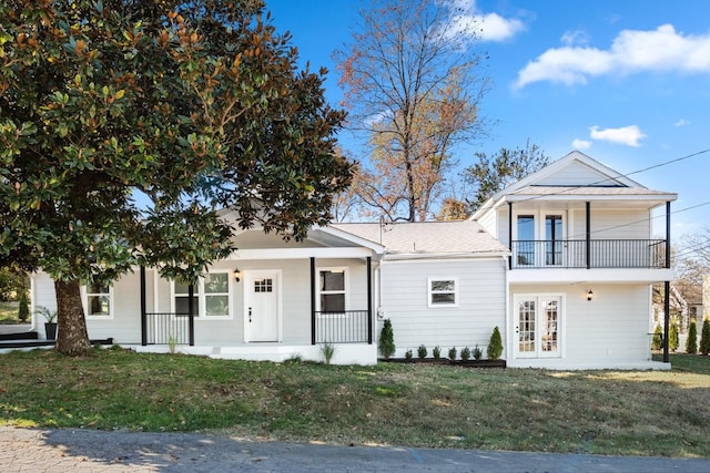 view of front facade featuring a porch, a balcony, french doors, and a front lawn