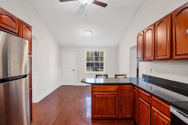 kitchen featuring stainless steel fridge, kitchen peninsula, dark wood-type flooring, and vaulted ceiling