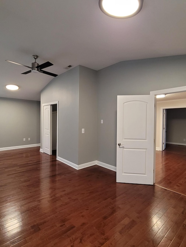 spare room with ceiling fan, dark wood-type flooring, and vaulted ceiling