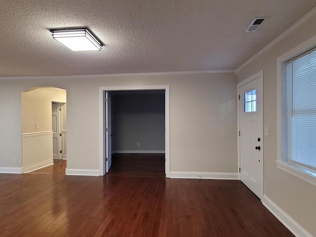 entrance foyer featuring dark wood-type flooring, a textured ceiling, and ornamental molding