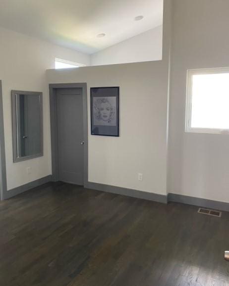 spare room featuring dark hardwood / wood-style flooring and vaulted ceiling