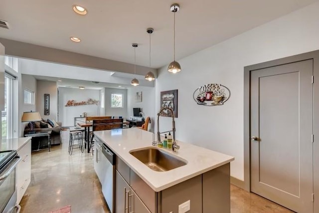 kitchen featuring sink, stainless steel dishwasher, stove, decorative light fixtures, and a center island with sink