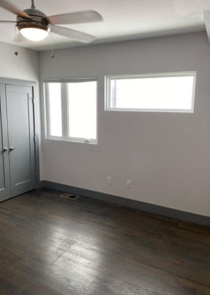 empty room with dark hardwood / wood-style floors, plenty of natural light, and ceiling fan