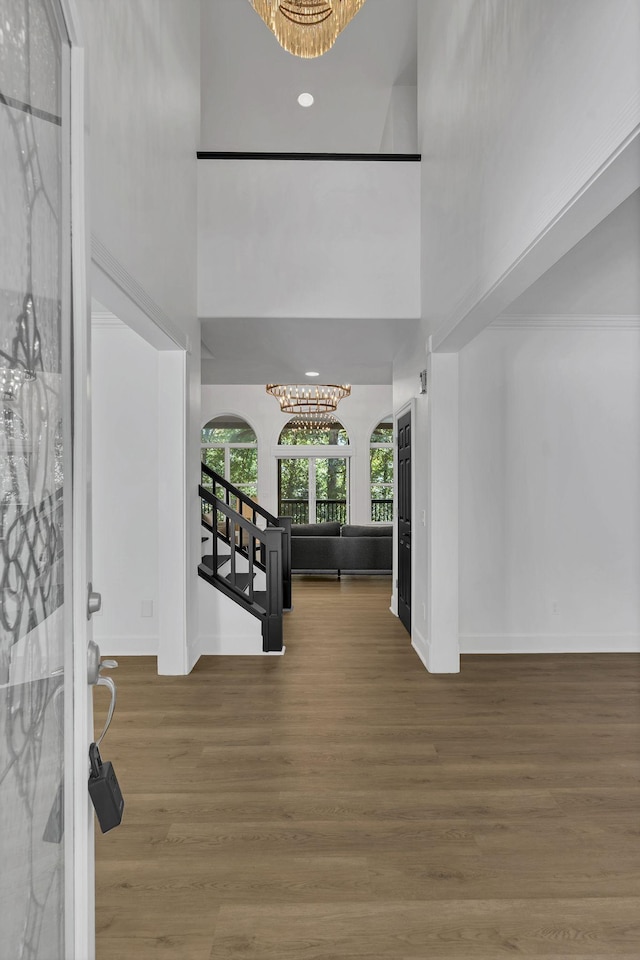 foyer entrance featuring a notable chandelier, wood-type flooring, and a high ceiling