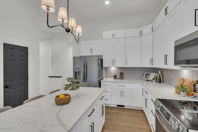 kitchen featuring tasteful backsplash, white cabinets, hanging light fixtures, and appliances with stainless steel finishes