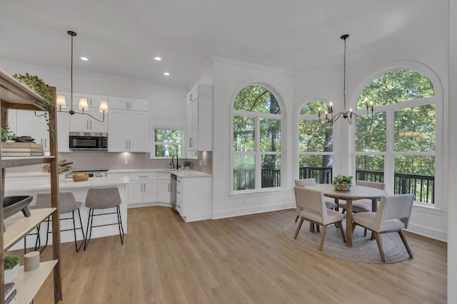 kitchen with white cabinets, decorative light fixtures, appliances with stainless steel finishes, and an inviting chandelier