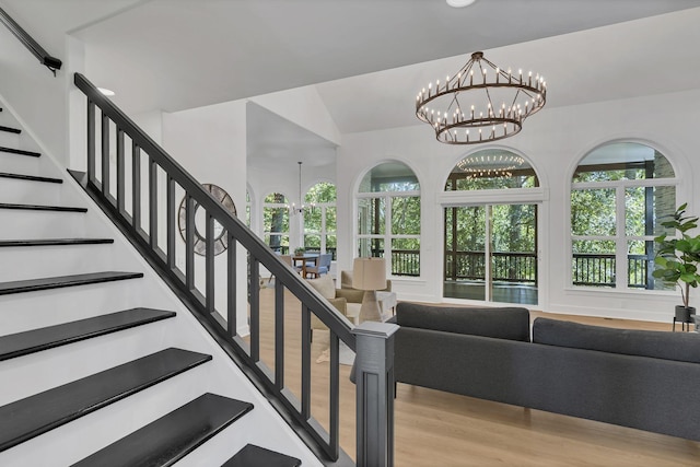 staircase featuring hardwood / wood-style floors, vaulted ceiling, and an inviting chandelier