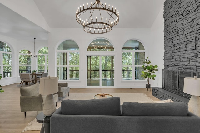 living room with a fireplace, light hardwood / wood-style floors, an inviting chandelier, and lofted ceiling