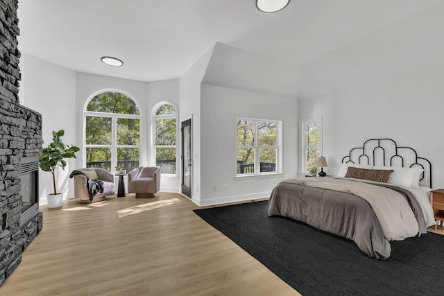 bedroom featuring a stone fireplace and light hardwood / wood-style flooring