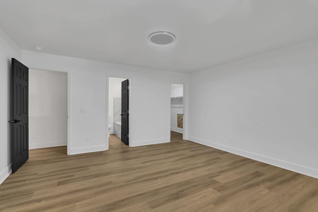 unfurnished bedroom with hardwood / wood-style flooring, a walk in closet, and a closet