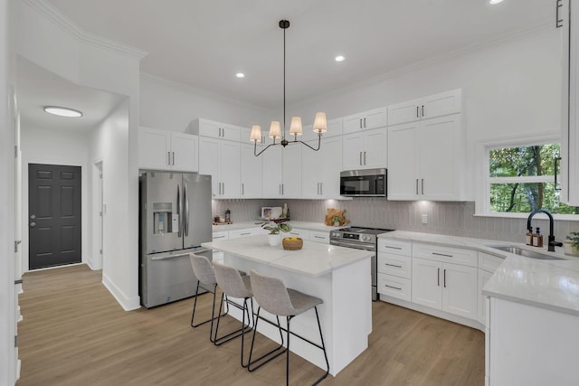 kitchen with white cabinetry, sink, a center island, hanging light fixtures, and appliances with stainless steel finishes