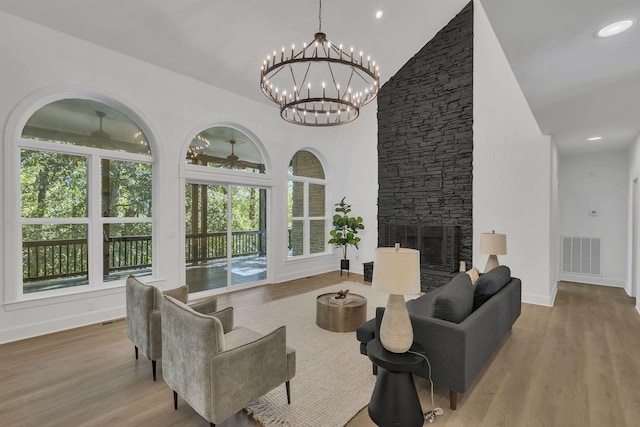 living room featuring ceiling fan with notable chandelier, light wood-type flooring, and a fireplace