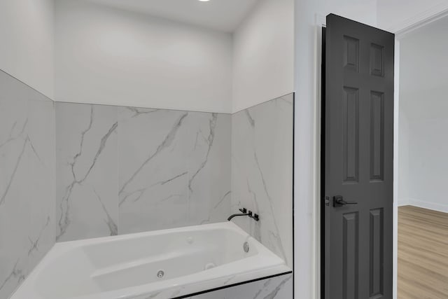 bathroom with hardwood / wood-style floors and tiled bath