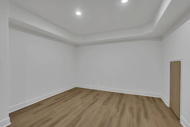 spare room with light hardwood / wood-style floors and a tray ceiling