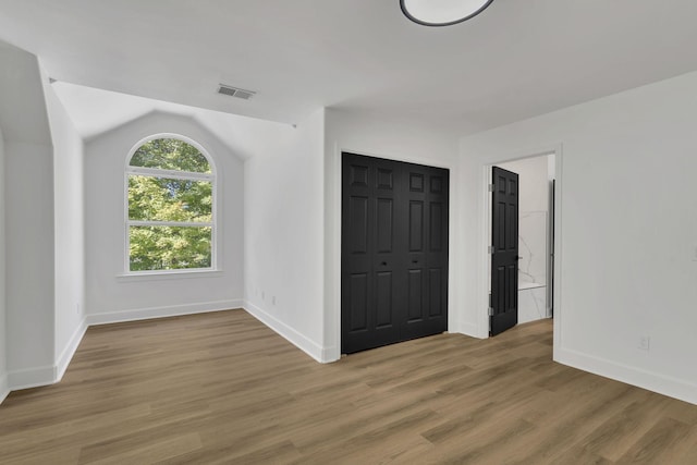 unfurnished bedroom featuring vaulted ceiling and light wood-type flooring