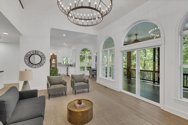 living room with a notable chandelier, light wood-type flooring, and vaulted ceiling