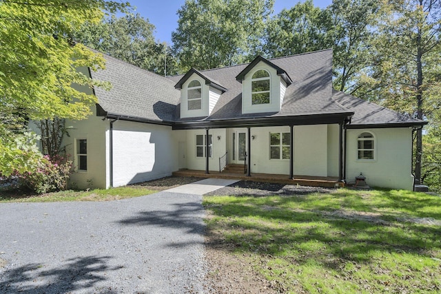 cape cod home featuring covered porch and a front lawn