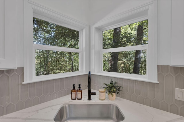 details featuring decorative backsplash, white cabinetry, light stone countertops, and sink