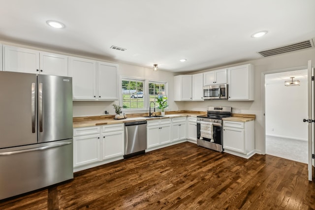 kitchen with butcher block countertops, sink, white cabinets, and appliances with stainless steel finishes