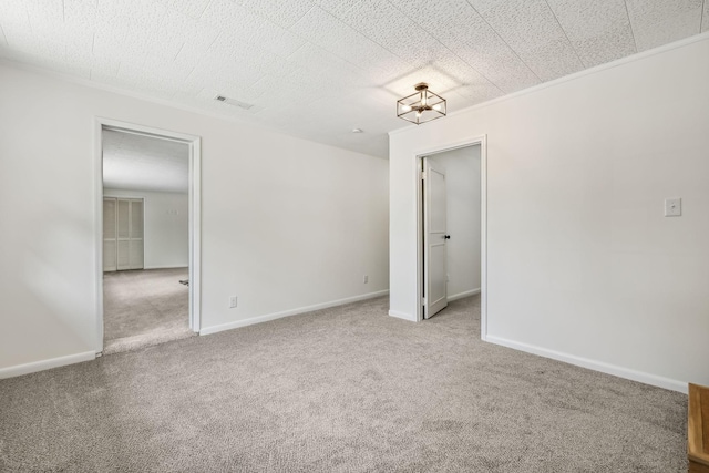 carpeted spare room with ornamental molding and a notable chandelier