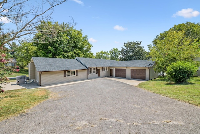 single story home featuring a garage, a front lawn, and cooling unit