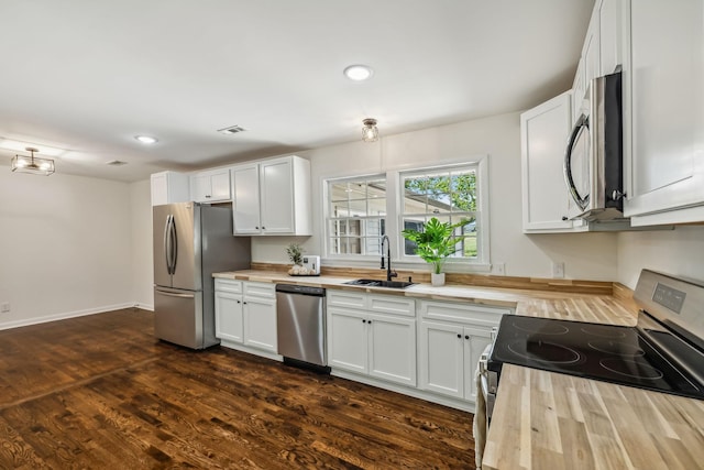 kitchen featuring butcher block countertops, white cabinetry, sink, and appliances with stainless steel finishes