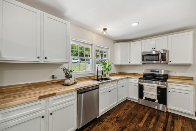 kitchen with butcher block counters, sink, stainless steel appliances, dark hardwood / wood-style flooring, and white cabinets