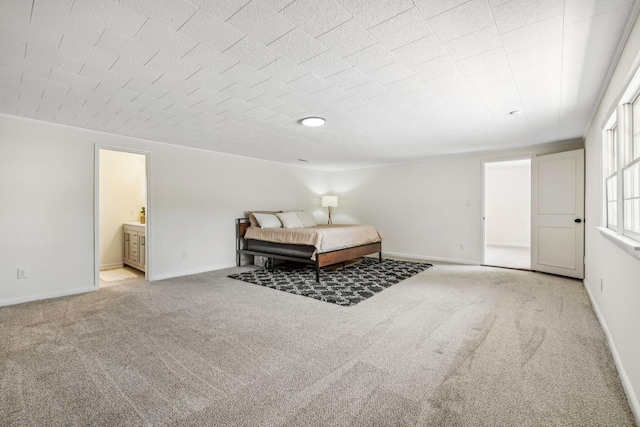 bedroom with ensuite bathroom and light colored carpet