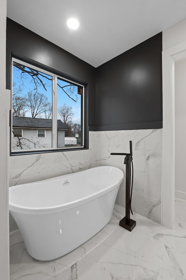 bathroom with a washtub and tile walls