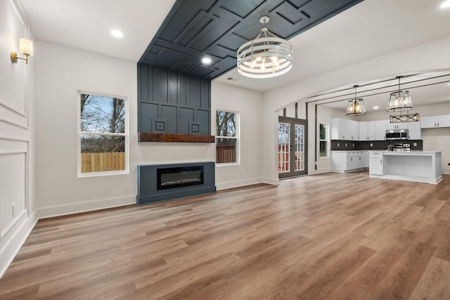 unfurnished living room with a chandelier, a healthy amount of sunlight, and light wood-type flooring