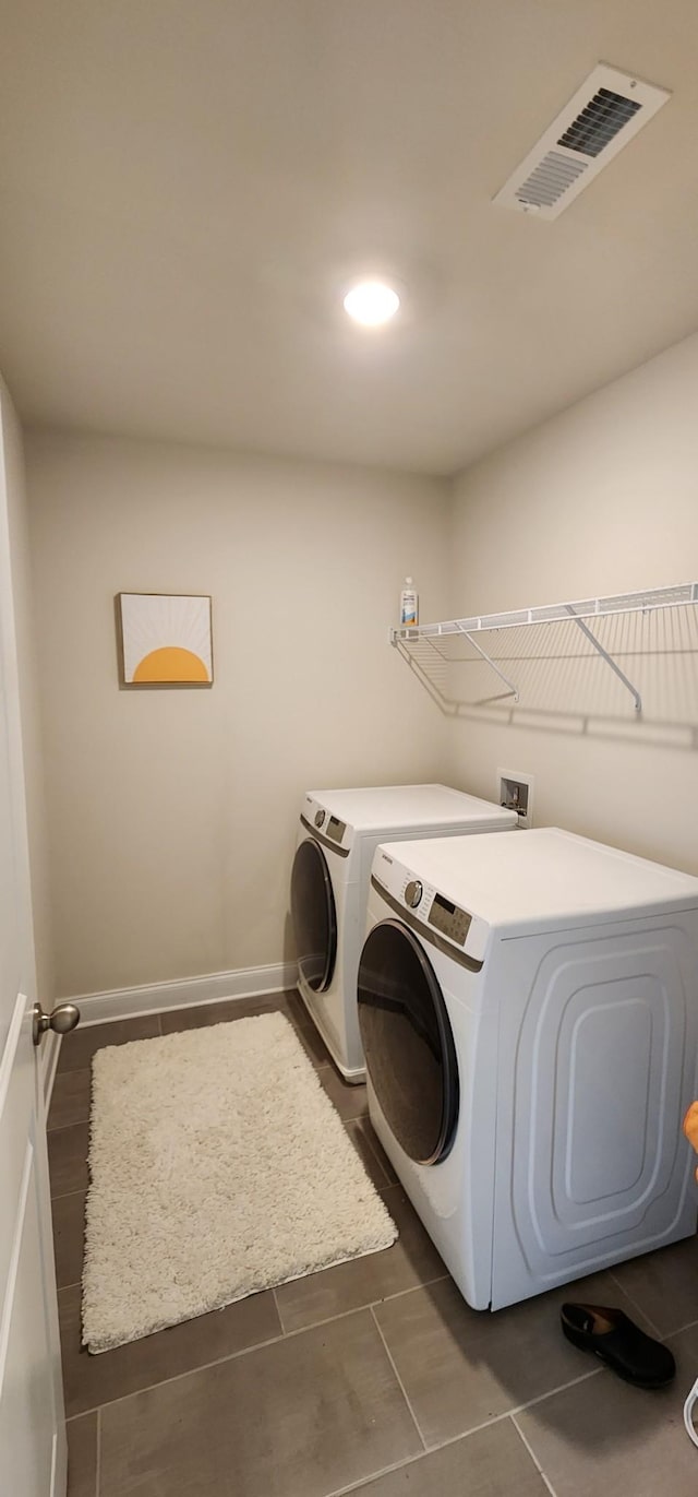 laundry area with dark tile patterned flooring and washer and clothes dryer