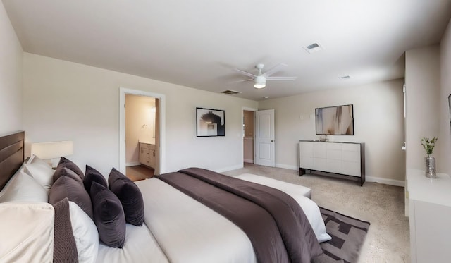 bedroom featuring ceiling fan, light colored carpet, and ensuite bath