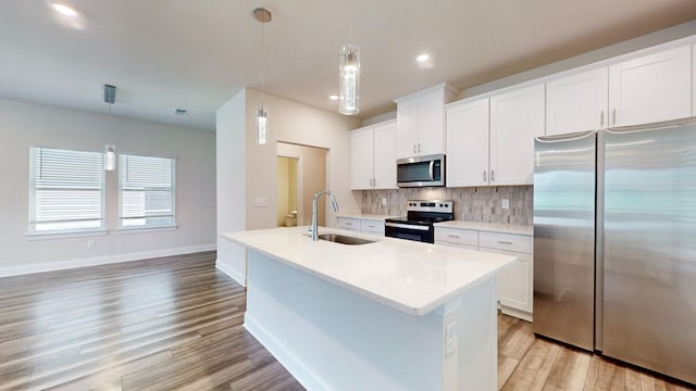 kitchen featuring white cabinets, appliances with stainless steel finishes, hanging light fixtures, and sink