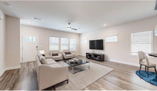 living room with ceiling fan, plenty of natural light, and light wood-type flooring