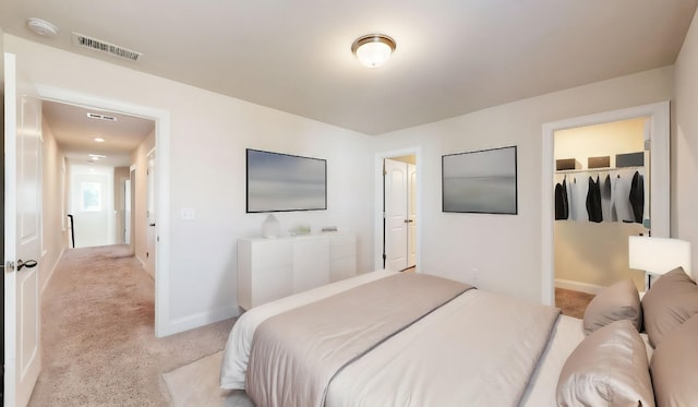 bedroom featuring a walk in closet, light carpet, and a closet