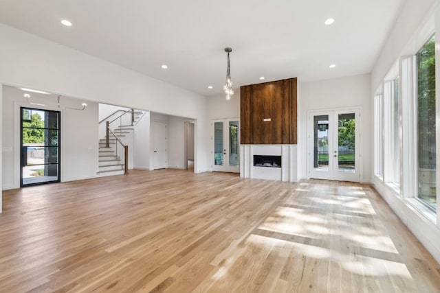 unfurnished living room with french doors, light hardwood / wood-style floors, and plenty of natural light