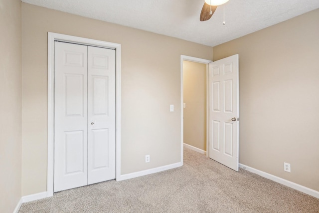 unfurnished bedroom featuring ceiling fan, a closet, and light carpet