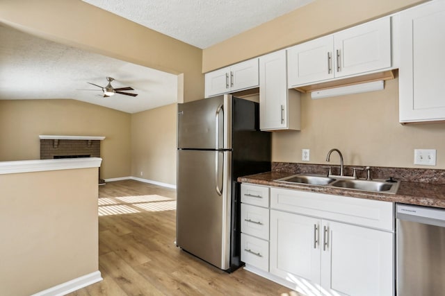 kitchen with sink, vaulted ceiling, ceiling fan, white cabinetry, and stainless steel appliances