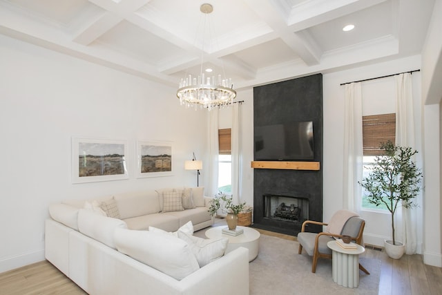 living room featuring beam ceiling, a chandelier, a large fireplace, and light hardwood / wood-style floors