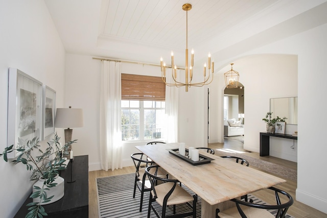 dining area with hardwood / wood-style flooring, a raised ceiling, wood ceiling, and a chandelier