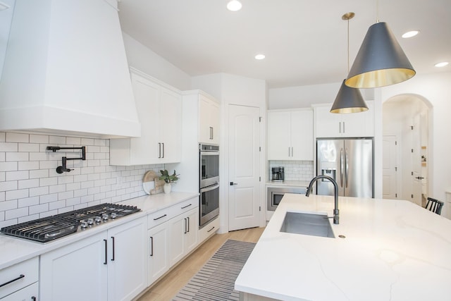 kitchen with tasteful backsplash, white cabinetry, pendant lighting, and stainless steel appliances